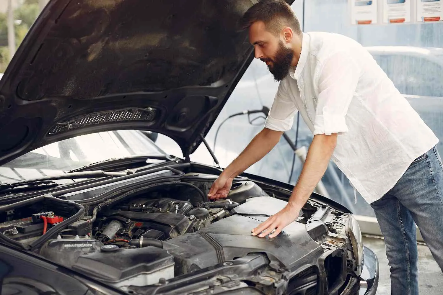Driver leaning over an open hood to check the engine
